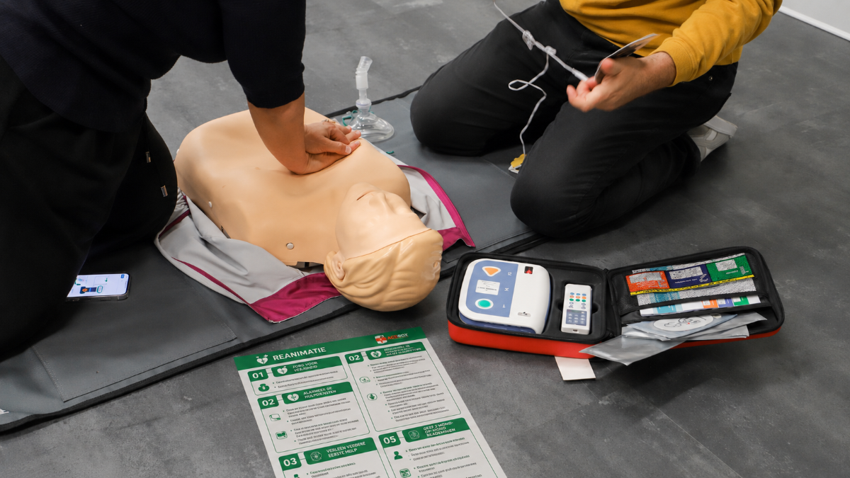 A person practicing CPR on a mannequin with a Actibox action card besides him